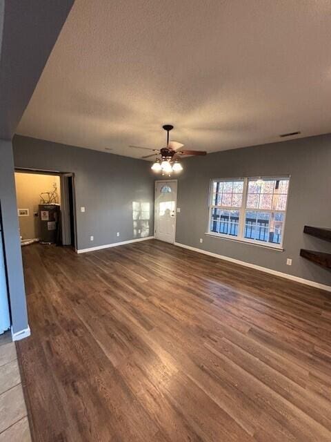 unfurnished living room featuring a textured ceiling, ceiling fan, and dark wood-type flooring