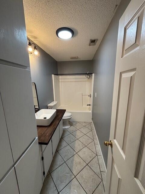 full bathroom featuring shower / bath combination, vanity, a textured ceiling, tile patterned flooring, and toilet