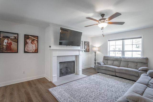 living room with ceiling fan, a fireplace, and wood-type flooring