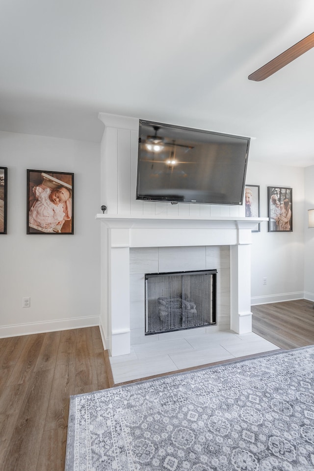 interior details with ceiling fan, a fireplace, and wood-type flooring