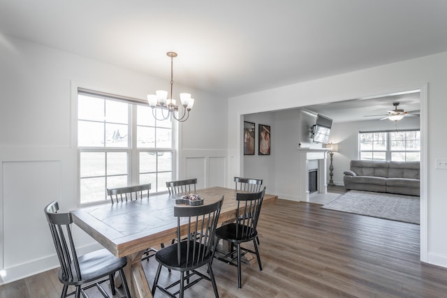 dining space with ceiling fan with notable chandelier and dark wood-type flooring