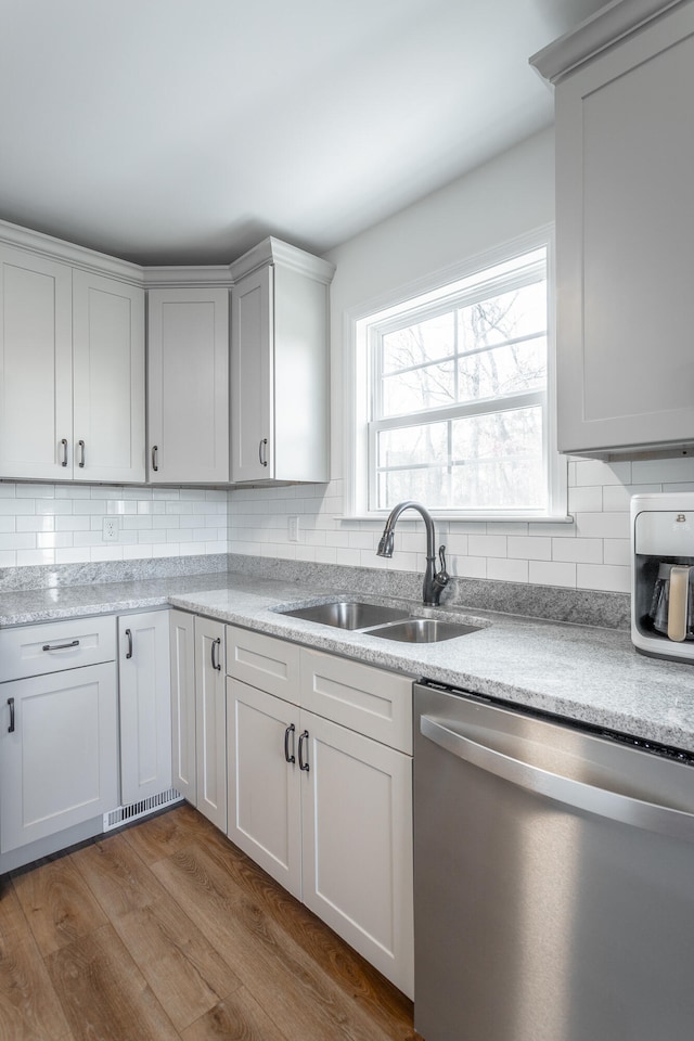 kitchen with backsplash, hardwood / wood-style flooring, dishwasher, and sink