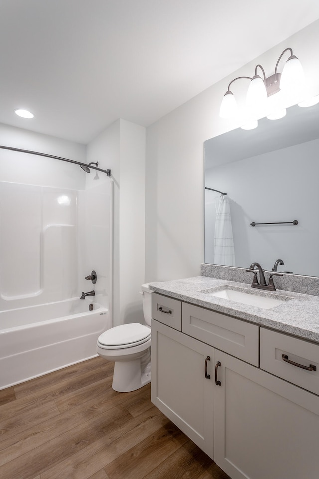 full bathroom featuring toilet, hardwood / wood-style floors, vanity, and shower / tub combo with curtain