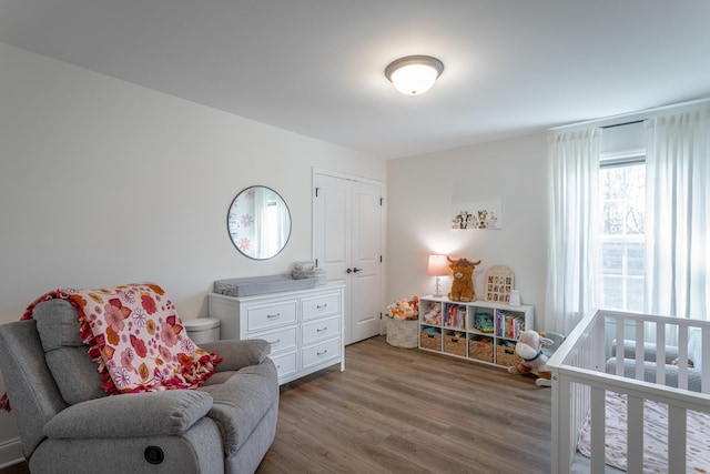 bedroom with a crib and wood-type flooring