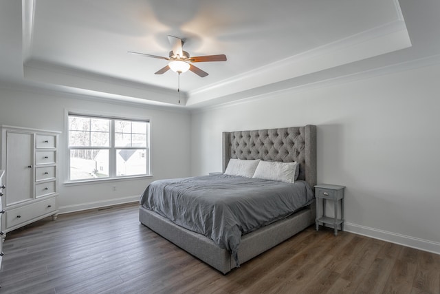 bedroom with dark hardwood / wood-style flooring, a raised ceiling, ceiling fan, and crown molding