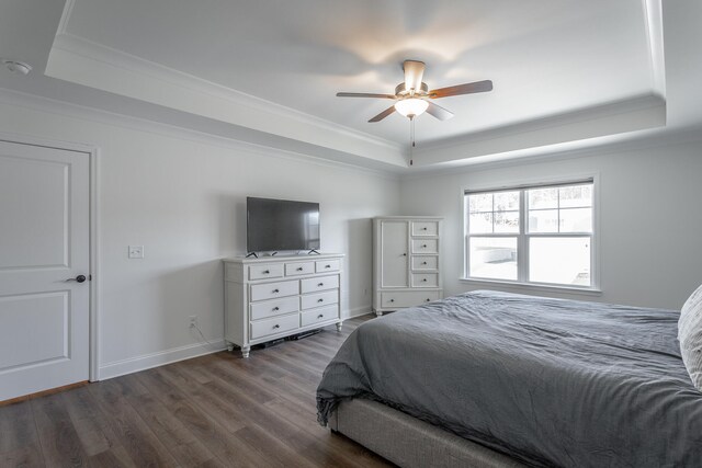 bedroom with a tray ceiling, dark hardwood / wood-style floors, ornamental molding, and ceiling fan