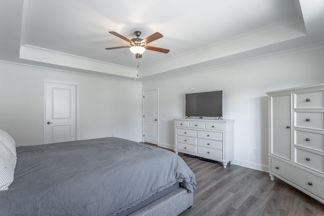 bedroom featuring ornamental molding, a tray ceiling, ceiling fan, and hardwood / wood-style flooring