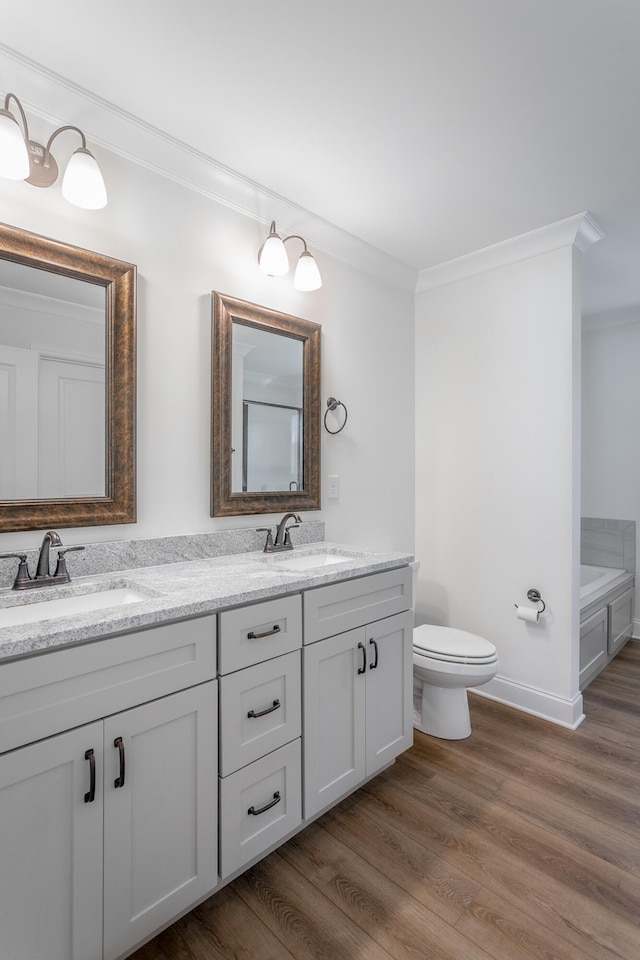 bathroom with toilet, hardwood / wood-style flooring, a bathtub, vanity, and ornamental molding