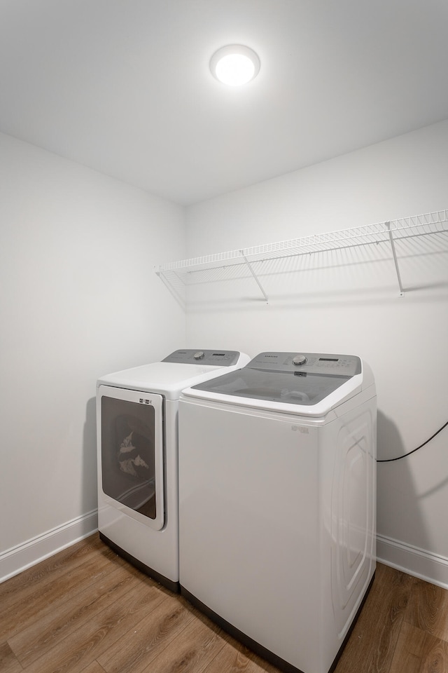 laundry area with washing machine and clothes dryer and hardwood / wood-style flooring