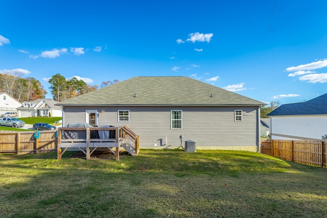 rear view of property with central air condition unit, a deck, and a lawn