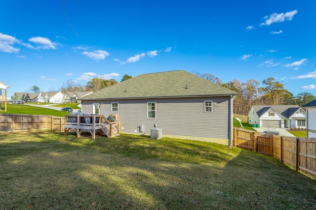 back of house featuring a lawn, a wooden deck, and central AC unit