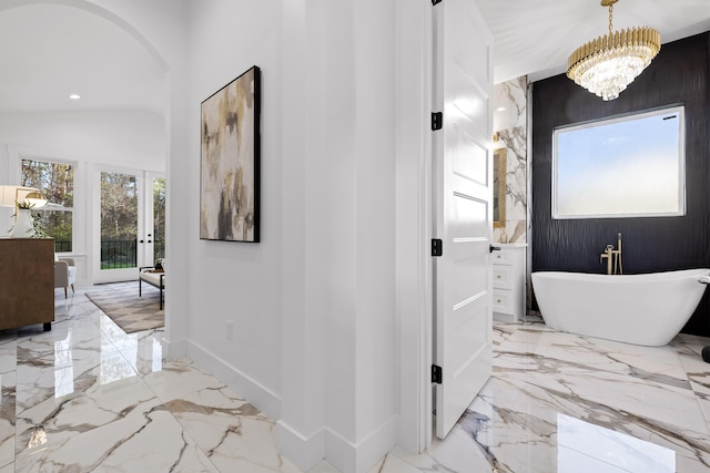 interior space featuring a bathing tub, an inviting chandelier, a wealth of natural light, and vaulted ceiling