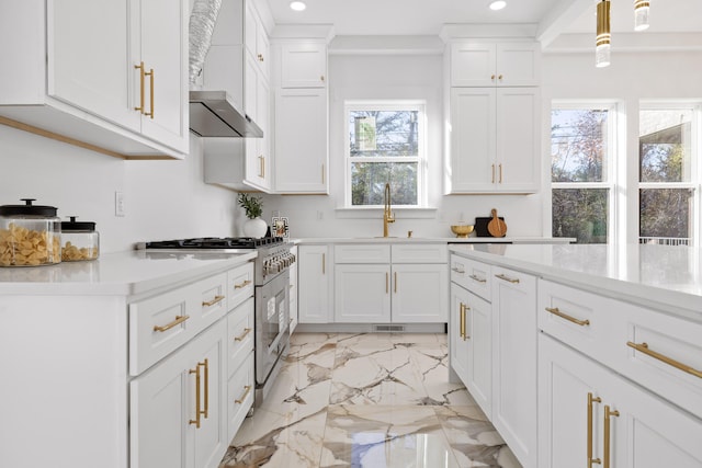 kitchen featuring white cabinets, sink, high end stainless steel range oven, and hanging light fixtures