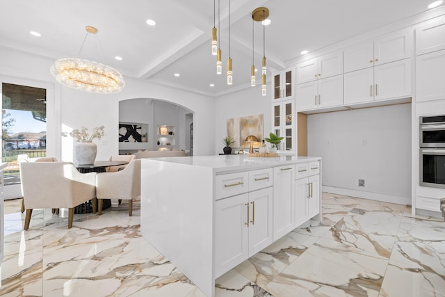 kitchen with an inviting chandelier, white cabinets, hanging light fixtures, double oven, and a kitchen island