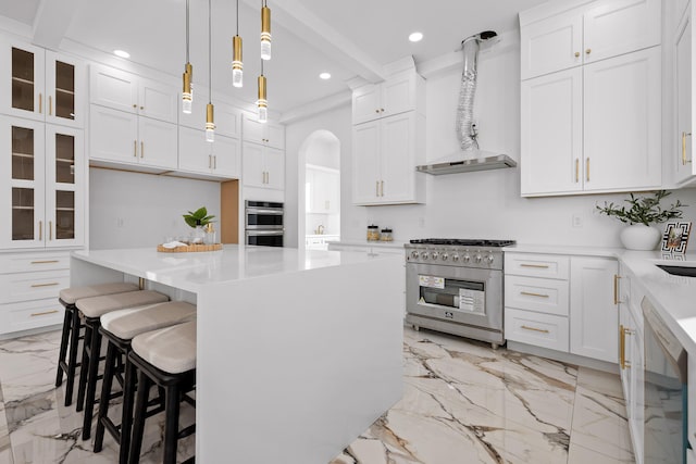 kitchen with a center island, white cabinetry, stainless steel appliances, and wall chimney range hood