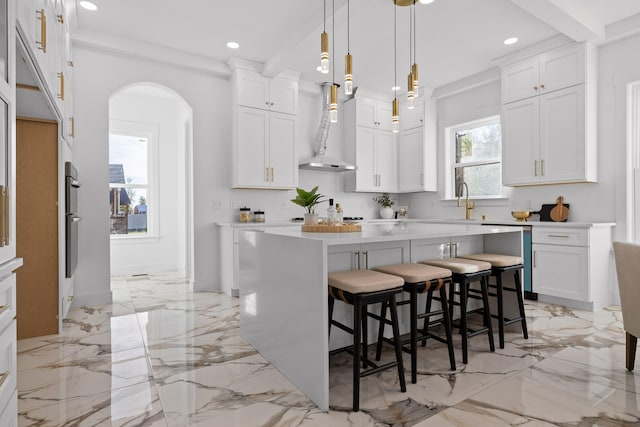 kitchen with a kitchen island, decorative light fixtures, a breakfast bar area, white cabinets, and appliances with stainless steel finishes