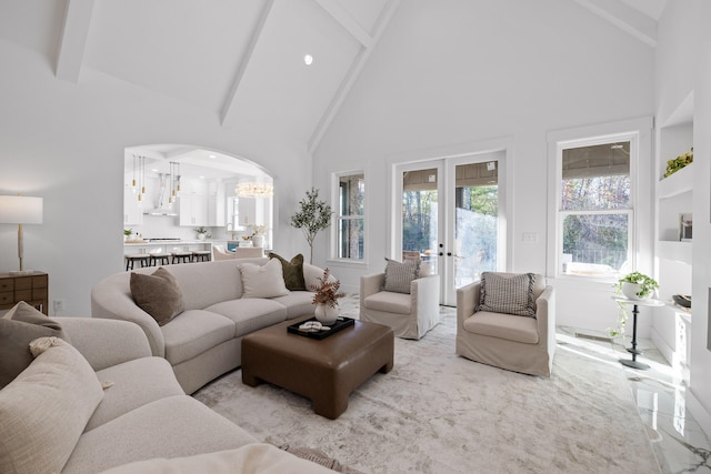 living room with a chandelier, beam ceiling, high vaulted ceiling, and french doors