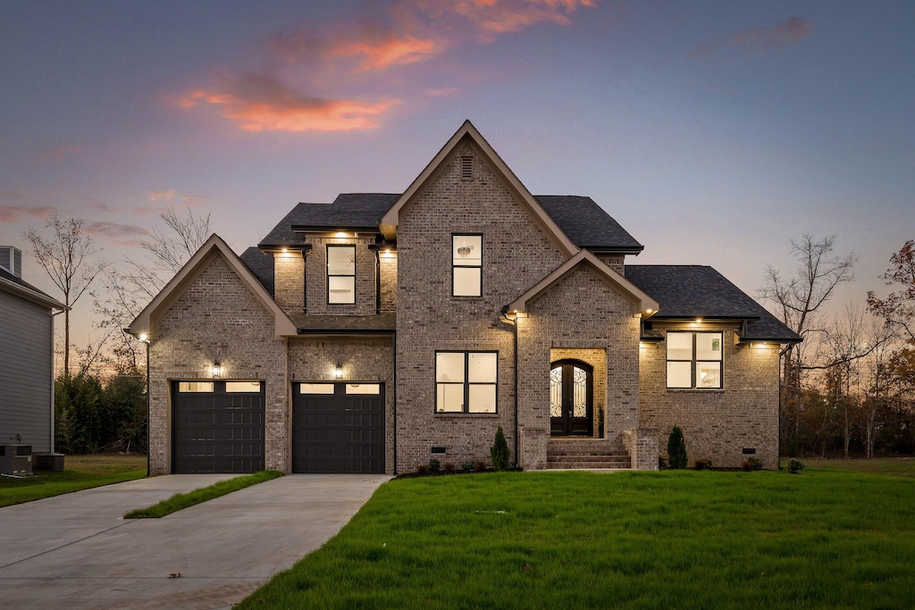 2209 Peterson Dr, Chattanooga, TN 37421 - view of front facade featuring brick siding, driveway, a yard, and french doors