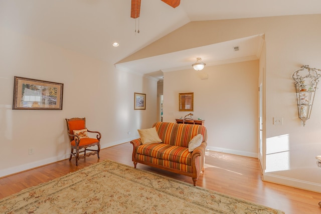 living area with ceiling fan, light wood-type flooring, ornamental molding, and vaulted ceiling