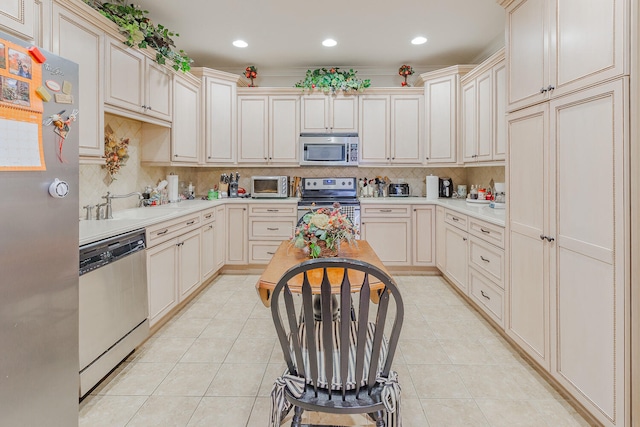 kitchen with light tile patterned floors, appliances with stainless steel finishes, and cream cabinets