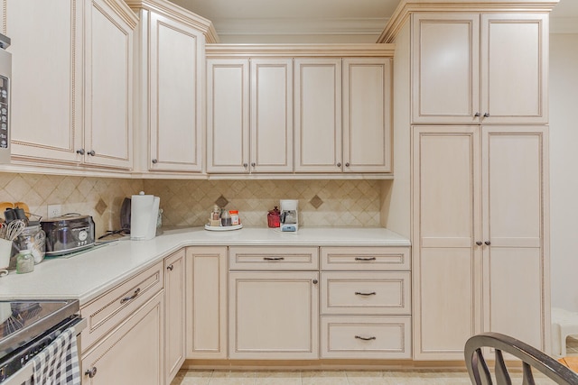 kitchen featuring decorative backsplash, cream cabinets, crown molding, and stainless steel range with electric stovetop