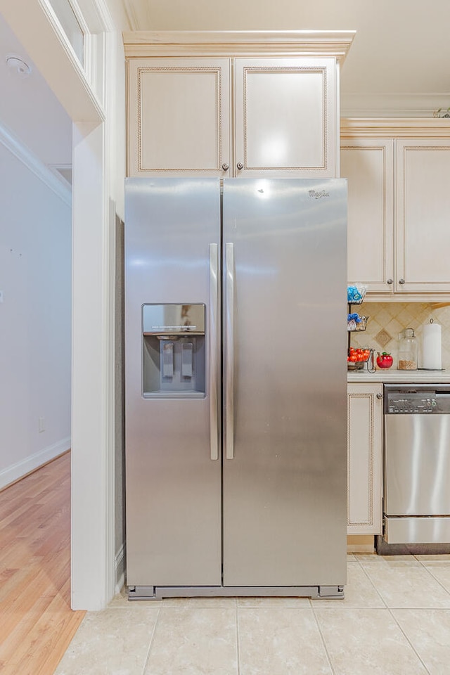 kitchen with decorative backsplash, stainless steel appliances, crown molding, light hardwood / wood-style flooring, and cream cabinetry