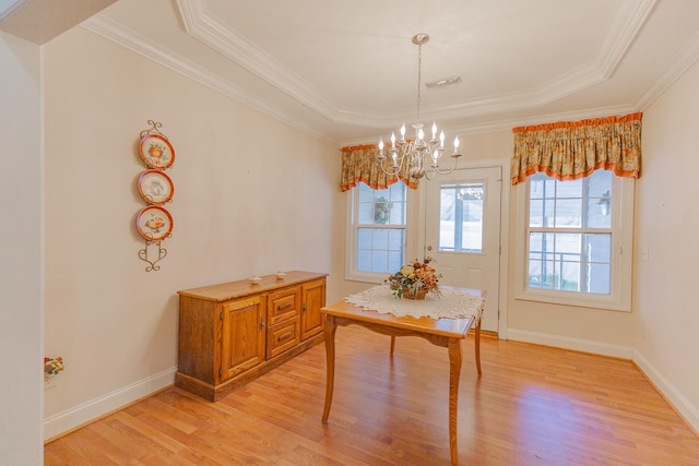 dining space with a chandelier, light wood-type flooring, a tray ceiling, and crown molding