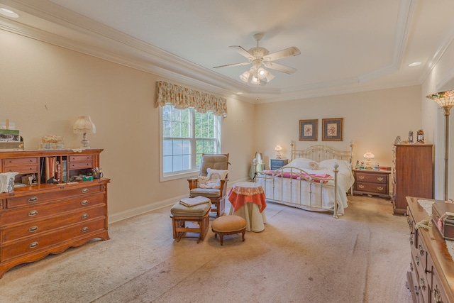 carpeted bedroom with ceiling fan, crown molding, and a tray ceiling