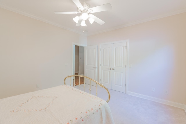 carpeted bedroom with ceiling fan, ornamental molding, and a closet