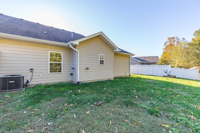 back of house featuring a lawn and central air condition unit