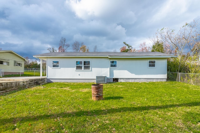 rear view of house featuring a lawn and central AC