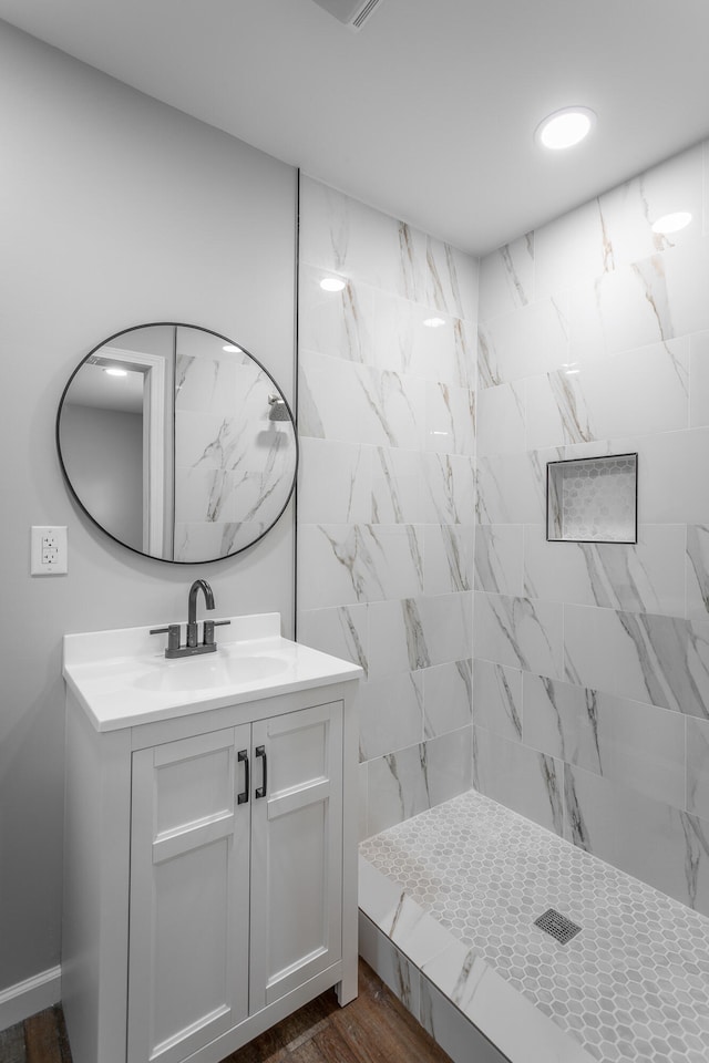 bathroom featuring tiled shower, hardwood / wood-style floors, and vanity