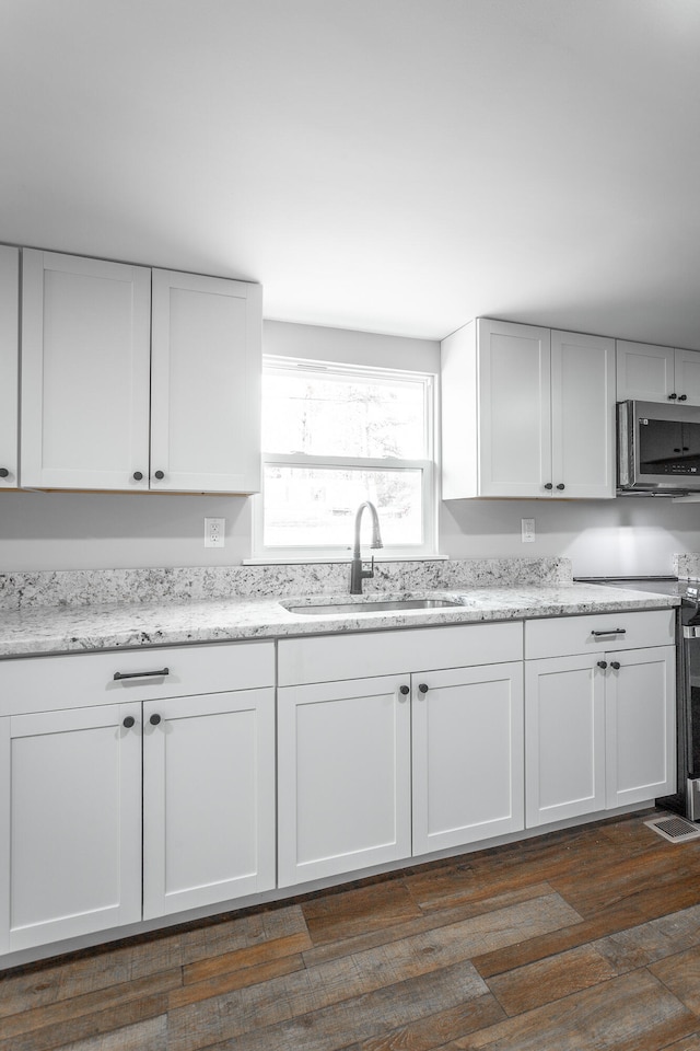 kitchen featuring stove, white cabinets, sink, dark hardwood / wood-style floors, and light stone counters