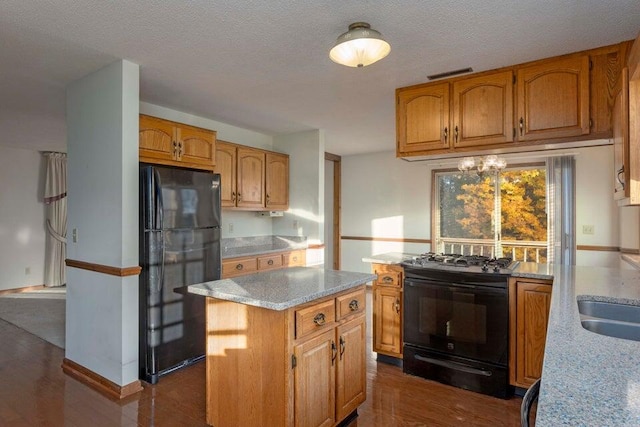 kitchen with black appliances, a kitchen island, dark hardwood / wood-style flooring, and a textured ceiling