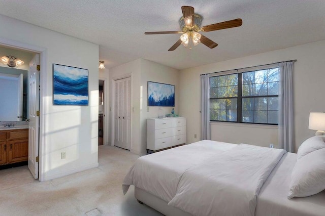 bedroom with connected bathroom, ceiling fan, light carpet, and a textured ceiling