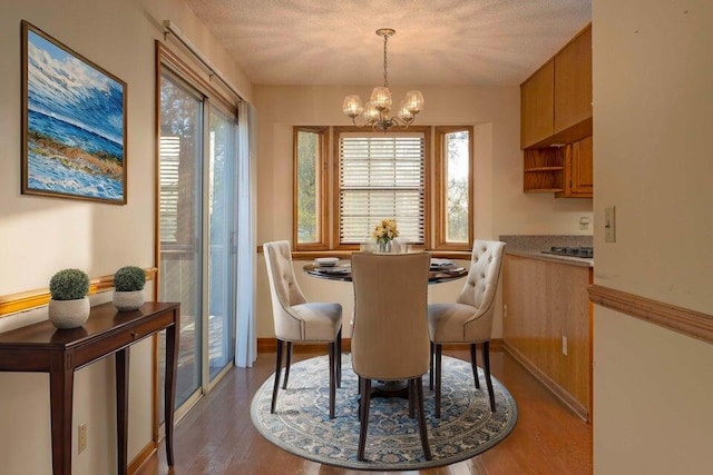 dining space with hardwood / wood-style floors, a textured ceiling, and an inviting chandelier