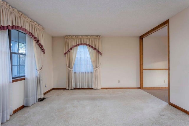 carpeted spare room featuring plenty of natural light and a textured ceiling