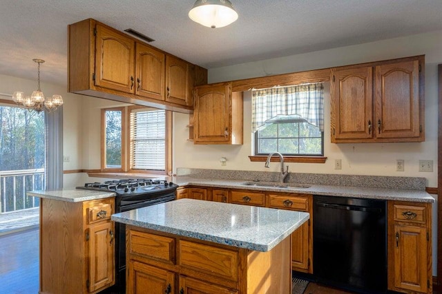 kitchen featuring a healthy amount of sunlight, a center island, black appliances, and an inviting chandelier