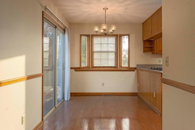 unfurnished dining area with hardwood / wood-style flooring, a textured ceiling, and an inviting chandelier