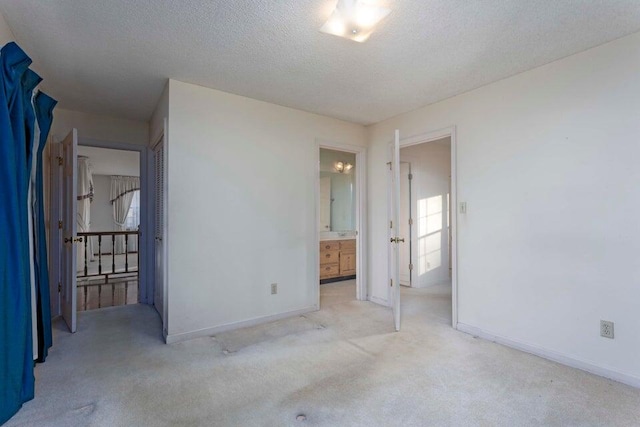 unfurnished bedroom with light carpet, a textured ceiling, and connected bathroom