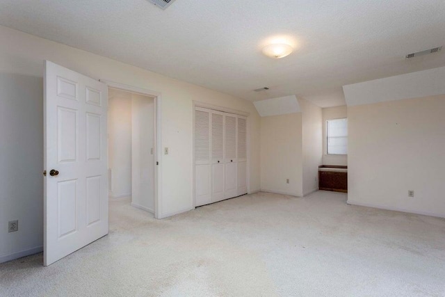 unfurnished bedroom with light colored carpet and a textured ceiling