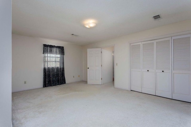 unfurnished bedroom featuring light carpet and a closet