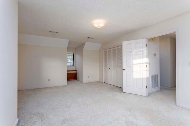 carpeted spare room with a textured ceiling and lofted ceiling