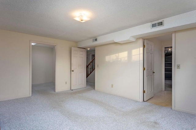 carpeted empty room featuring a textured ceiling