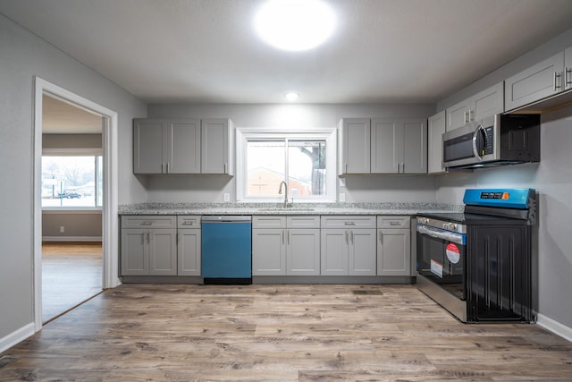 kitchen with sink, stainless steel range with electric cooktop, gray cabinetry, dishwasher, and light hardwood / wood-style floors