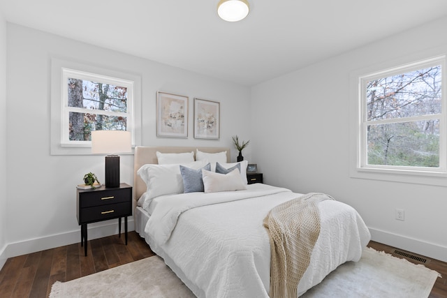 bedroom featuring multiple windows and dark wood-type flooring