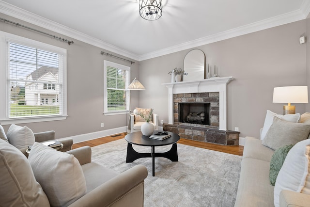 living room with a stone fireplace, a wealth of natural light, light hardwood / wood-style flooring, and crown molding