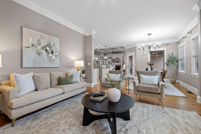 living room with wood-type flooring, a notable chandelier, and ornamental molding