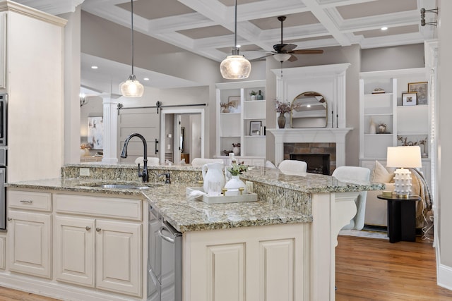 kitchen featuring ceiling fan, sink, a barn door, decorative light fixtures, and light hardwood / wood-style flooring