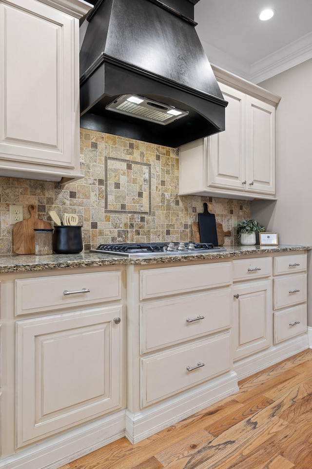 kitchen featuring backsplash, light hardwood / wood-style flooring, ornamental molding, and custom exhaust hood